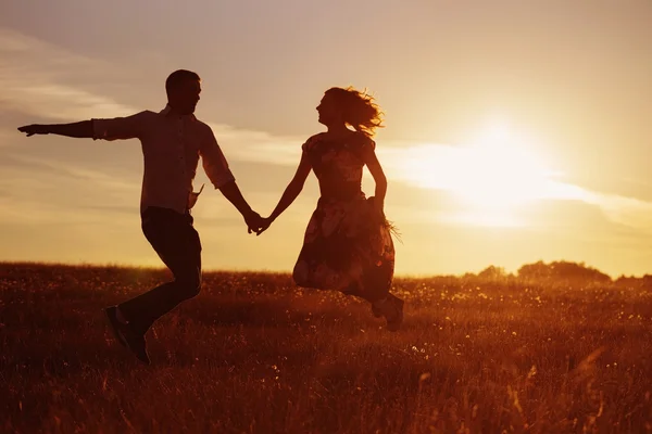 Young happy couple jumping on sunset — Stock Photo, Image