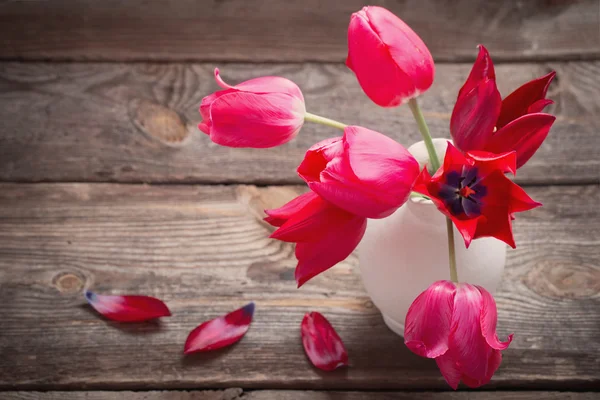 Červené tulipány na staré dřevěné pozadí — Stock fotografie