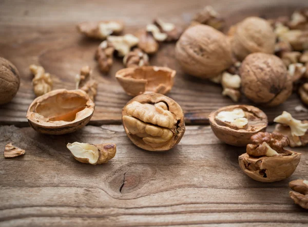 Ядра грецкого ореха и целые грецкие орехи на деревенском старом деревянном столе — стоковое фото