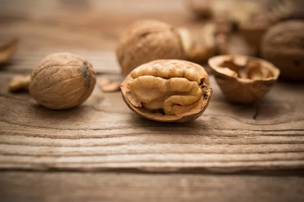 Gherigli di noce e noci intere su un vecchio tavolo di legno rustico — Foto Stock