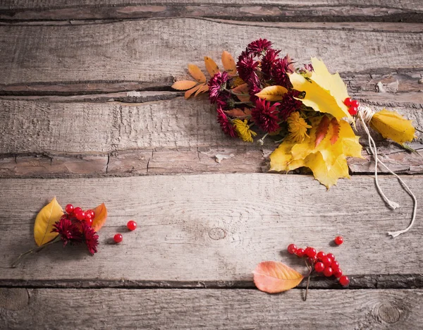 Autumn flowers and leaves on wooden background — Stock Photo, Image