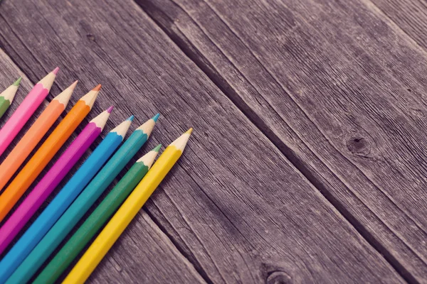 Різнокольорові олівці на дерев'яному фоні — стокове фото