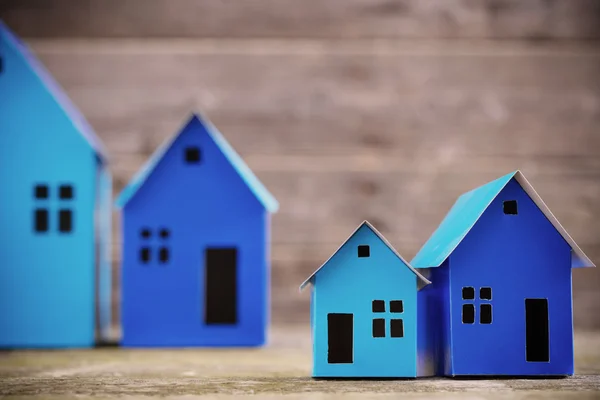 Una casa di carta si erge su uno sfondo di legno — Foto Stock