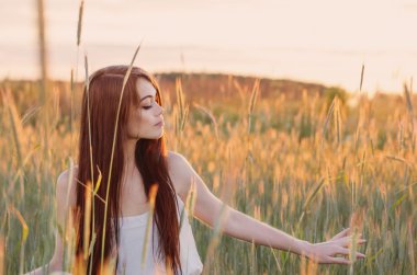 Gün batımında buğday alanında güzel esmer kadın