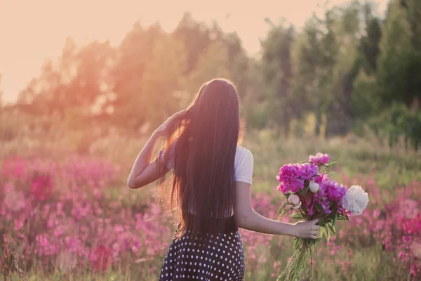 Brunette fille avec des fleurs au coucher du soleil — Photo