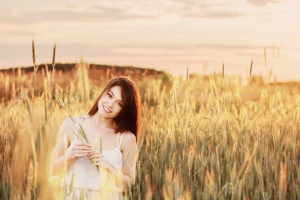 Krásná bruneta žen v pšeničné pole při západu slunce — Stock fotografie