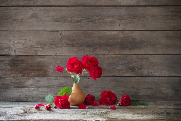 Czerwona róża w wazonie na podłoże drewniane — Zdjęcie stockowe