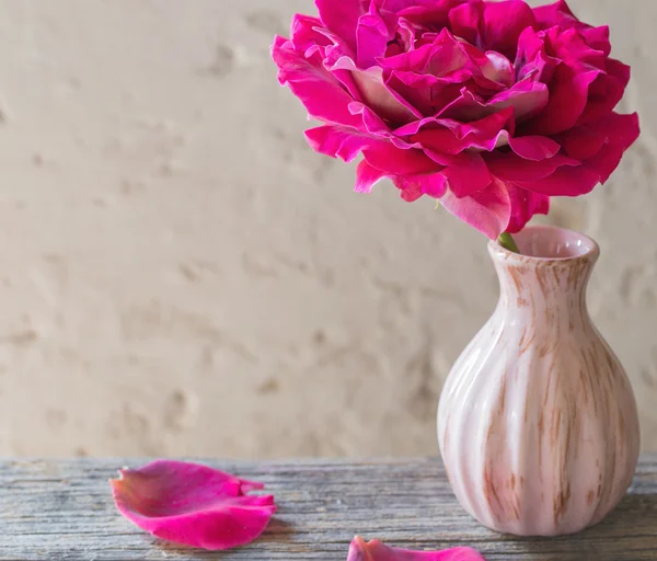 Rosa rosa en un jarrón sobre fondo rústico viejo — Foto de Stock