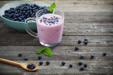 Eski ahşap arka plan üzerinde yaban mersini ile yoğurt