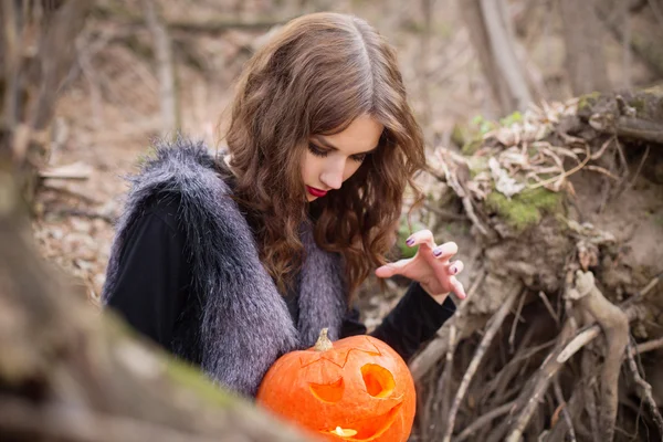 Beautiful witch with a pumpkin in forest — Stock Photo, Image