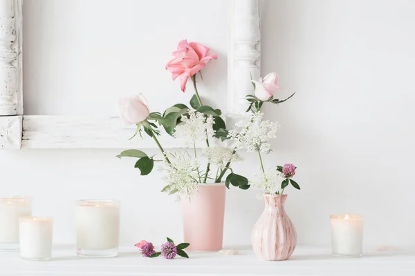 Bloemen in een vaas en kaarsen op witte achtergrond — Stockfoto