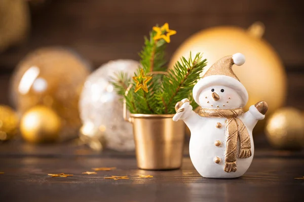 Christmas golden decorations and snowman on dark wooden background