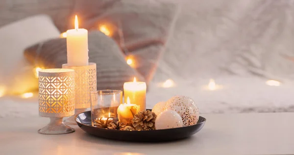圣诞装饰 白色的桌子上燃着蜡烛 沙发的背衬着长椅和枕头 舒适的家和假日的概念 — 图库照片