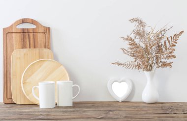 Beyaz mutfakta iki fincan ve kurutulmuş çiçekler.