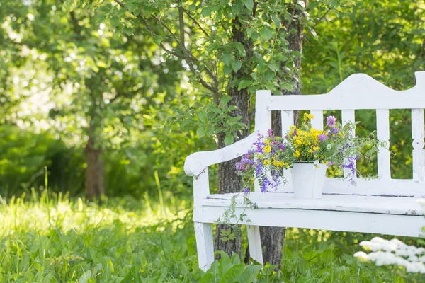 夏の庭の白い木のベンチに野生の花 — ストック写真