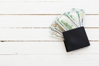 Beyaz ahşap arka planda siyah cüzdan dolar.