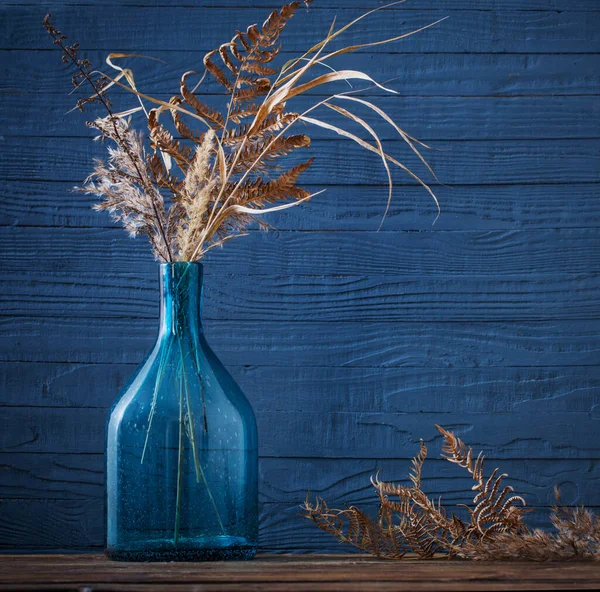 Gedroogde Bloemen Glazen Vaas Houten Tafel Blauwe Achtergrond — Stockfoto
