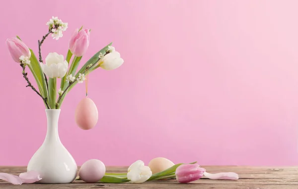 イースターエッグとチューリップの花瓶ピンクの背景 — ストック写真