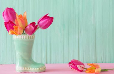 Yeşil ahşap arka planda vazoda pembe laleler