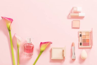 Parfümlü dekoratif kozmetik ürünler ve pembe arka planda çiçekler