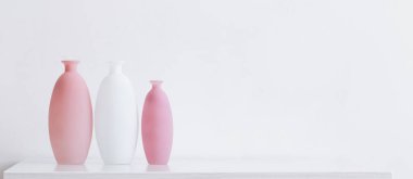 Beyaz ahşap raflarda modern pembe ve beyaz vazolar