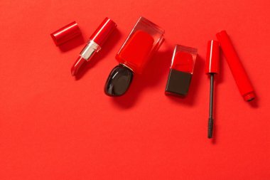 Kırmızı arka planda kırmızı parfüm şişesi ve kozmetik ürünleri