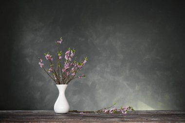 Vazodaki Daphne çiçekleri arka plandaki eski ahşap masada, karanlık duvarda.