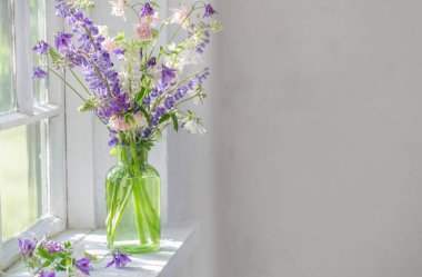 Vazodaki yaz çiçekleri güneş ışığında pencere eşiğinde