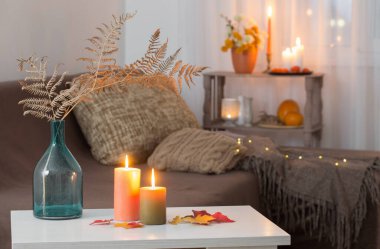 Evdeki beyaz masada sonbahar dekoru ile mum yakmak.