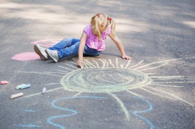 Küçük kız kaldırımda tebeşirle çiziyor