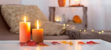 Evdeki beyaz masada sonbahar dekoru ile mum yakmak.