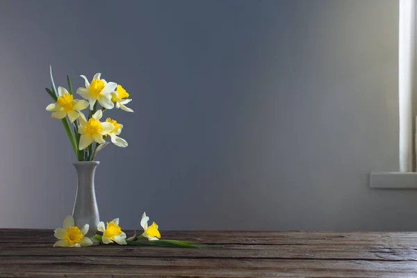 黄色のナルシシズムを背景に木のテーブルの上の花瓶に — ストック写真