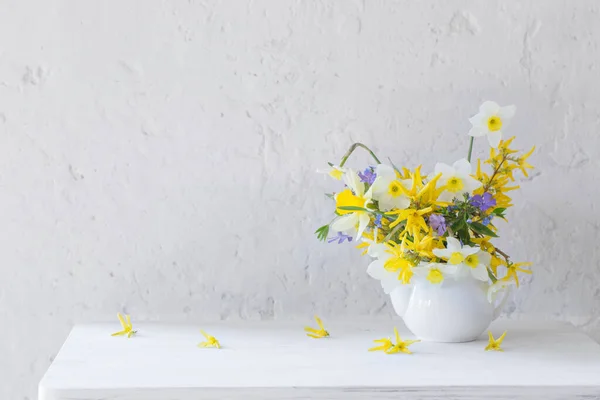 白い背景の木のテーブルの上に花瓶に白と黄色の春の花 — ストック写真