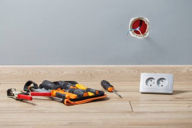 Gri duvara bir elektrik prizi yerleştiriliyor