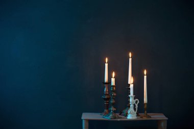 Koyu mavi arkaplanda yanan mumlarla şamdanlar