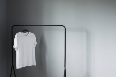 Gri duvara asılı beyaz tişört
