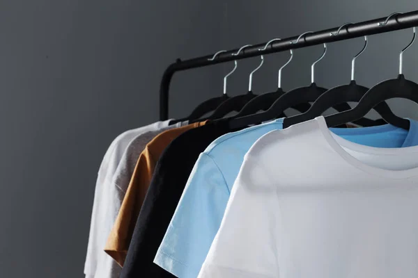 Gri Duvara Asılı Siyah Askı Üzerine Nötr Renkli Tişörtler — Stok fotoğraf