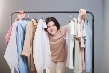 Yazlık kıyafetlerin yanındaki genç kız evde askıda.