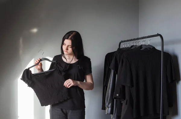 Nastolatka Dziewczyna Czarnych Dżinsach Shirt Pobliżu Wieszaka Czarnymi Ubraniami — Zdjęcie stockowe