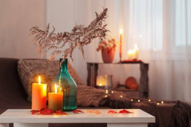 Evdeki beyaz masada sonbahar dekoru ile mum yakmak.