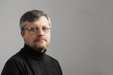 Gri arka planda sakallı olgun bir adam.