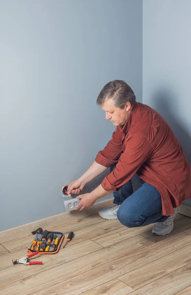 Man Installeert Een Stopcontact Grijze Wand — Stockfoto