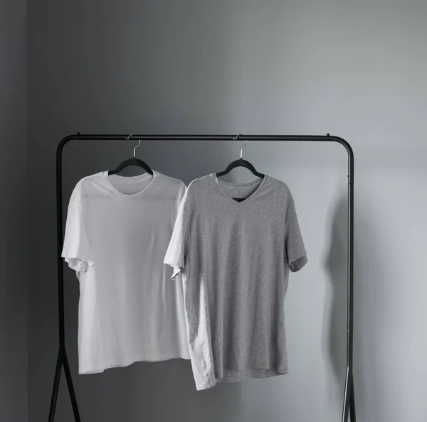 Duas Camisetas Cores Neutras Cabide Preto Contra Parede Cinza — Fotografia de Stock