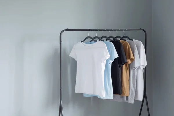 Shirts Neutralen Farben Auf Schwarzem Kleiderbügel Gegen Graue Wand — Stockfoto