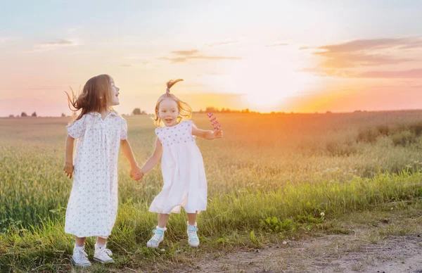Twee Kleine Meisje Springen Het Veld Bij Zonsondergang — Stockfoto