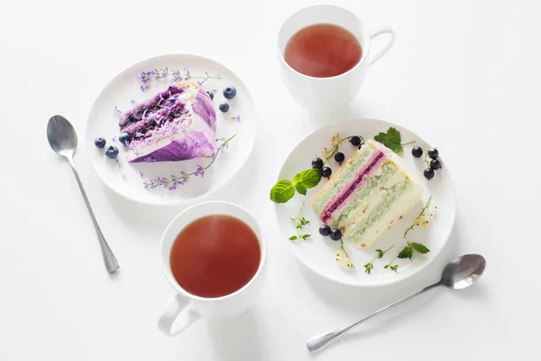 浆果芝士蛋糕和两杯茶放在白桌上 — 图库照片