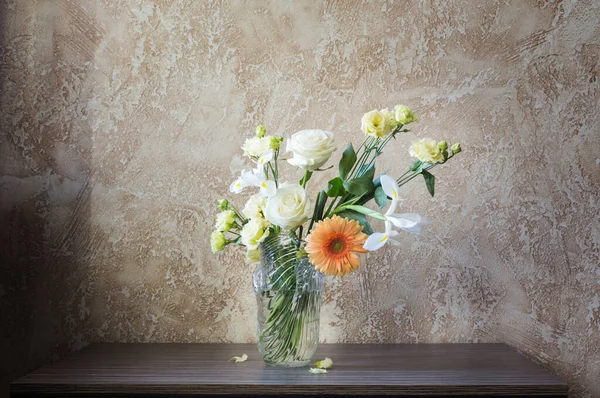 背景の壁のテーブルの上のガラス花瓶の花束 — ストック写真
