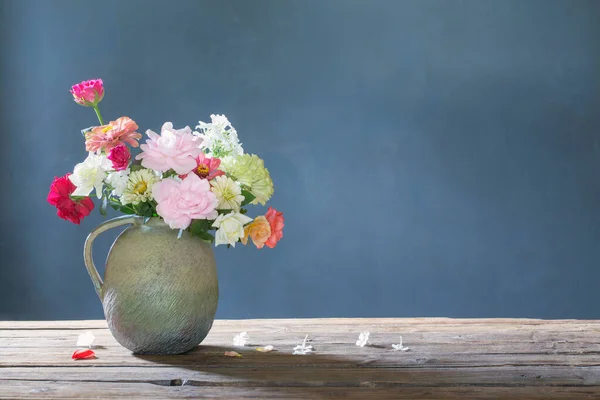 蓝色背景的木制桌子上陶瓷壶中的夏花 — 图库照片