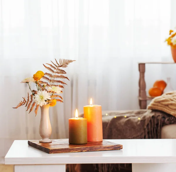 在家里的白桌子上点燃着点缀着秋天装饰的蜡烛 — 图库照片