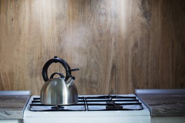 Mutfaktaki gazlı ocağın üzerinde modern metal çaydanlık.